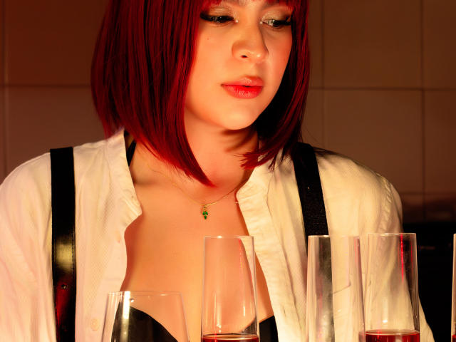 SamanthaEva69 with red bob, white shirt, black bra, holding glasses, cute face, subtle makeup, necklace, warm light, slightly open shirt, soft smile, medium tits.