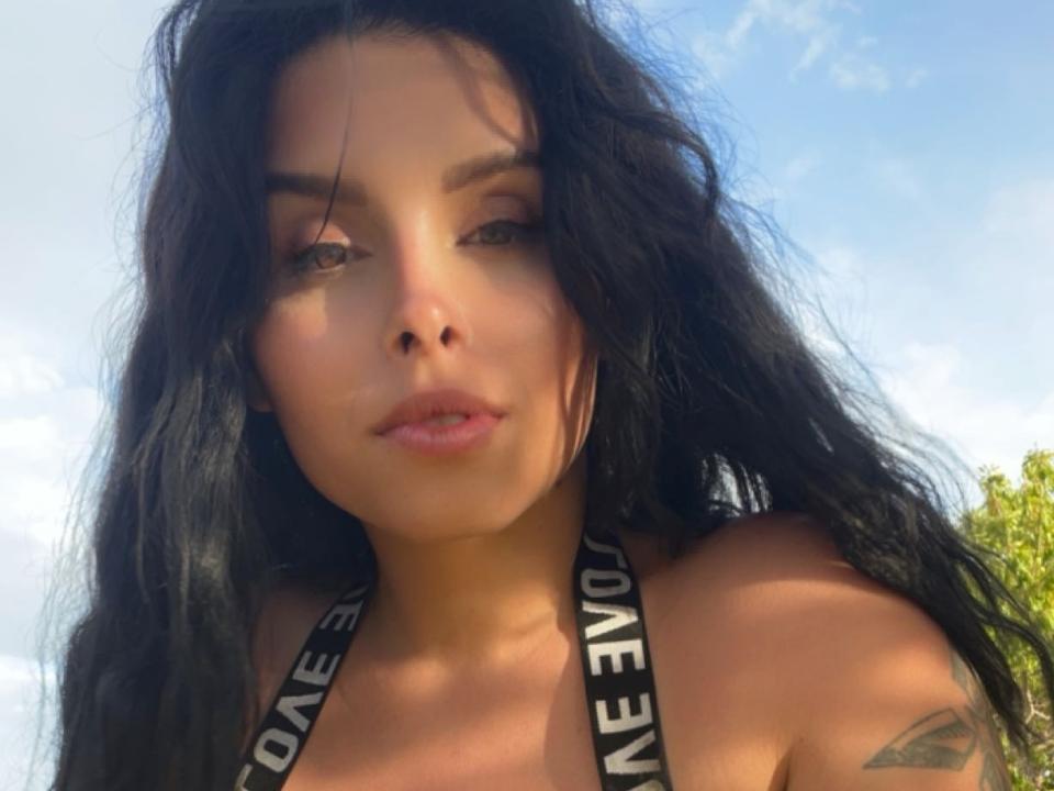 Brianna heeft lang, rommelig zwart haar, een bruine huid en een tatoeage op haar rechter schouder. Ze draagt een zwarte haltertop met "NICE" op de bandjes en kijkt naar beneden..