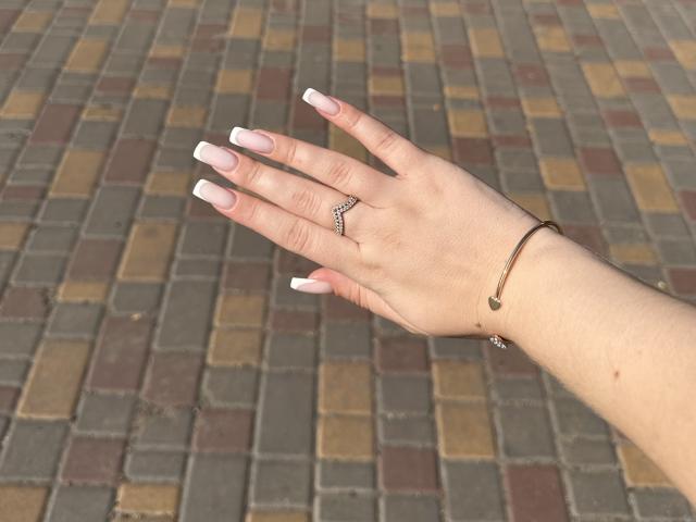 SugarrX's hand with long pink and white nails, a zigzag ring, and a thin bracelet, palm up, showing off her manicure and jewelry.