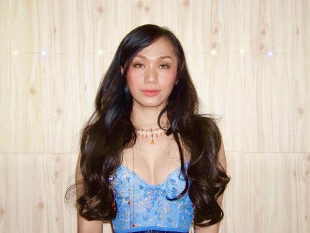 A flat, three-dimensional letter "L" in a bold, blocky style. The letter is centered, with a small blue dot at the bottom. The color is light beige.