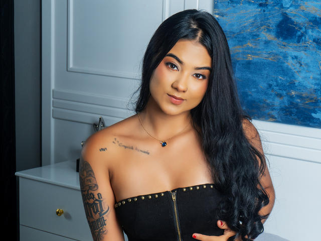 TamaraSummer heeft lang zwart haar, een bruine huid en een schattig gezicht met subtiele make-up. Ze draagt een zwarte top zonder bandjes, waardoor haar kleine borsten en een tatoeage op haar linkerarm zichtbaar zijn..