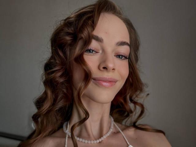 UnderTheSkin ha i capelli castano ondulati, gli occhi verdi e un leggero sorriso. Indossa una collana di perle, appare carina con le labbra rosa lucide. Ha il seno piccolo ed è attraente..