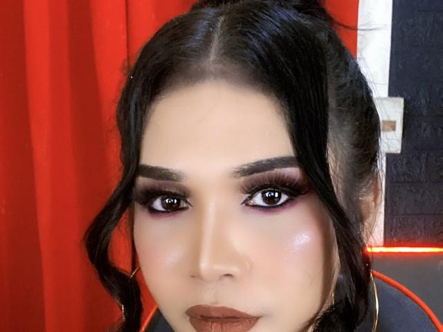 LexiSmithX has dark, wavy hair, thick eyebrows, and big brown eyes with heavy eyeliner and purple eyeshadow. She has a light skin tone and full, brown lips.