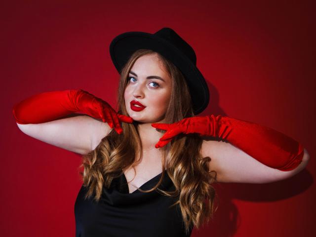 EsterMiln with red gloves, black hat, and red lipstick, holding her tits, looking sideways, wavy brown hair, red background, wearing black dress, sexy and confident.