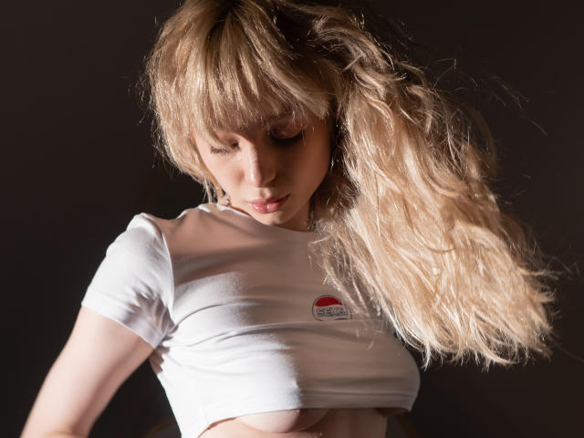 LisaMetalHoney with blonde hair, white shirt, exposed small tits, raised arms, looking down, dark background, soft lighting, textured hair, subtle shadow on face.