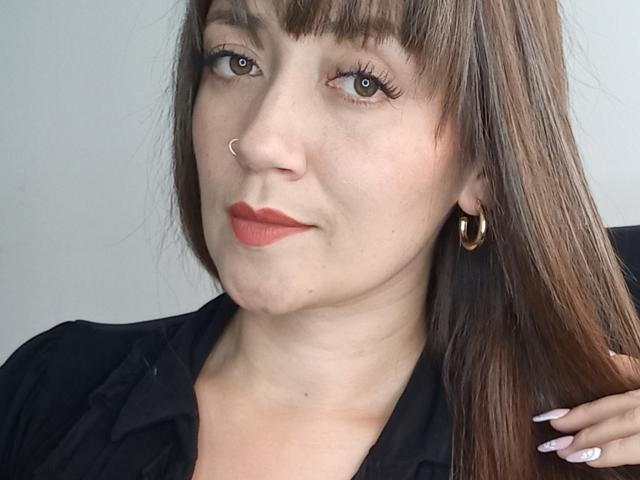 LaFrancaiseJessy with wavy brown hair, red lipstick, and a loose blue dress, slumped on a keyboard, her tits slightly visible, right strap down, eyes half-open.