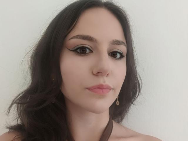 AshleyCrystal heeft bleke huid, donker golvend haar, dikke wenkbrauwen, zwarte eyeliner, roze lippen, een kleine neus en een neutrale uitdrukking. Ze draagt een eenvoudige ketting..