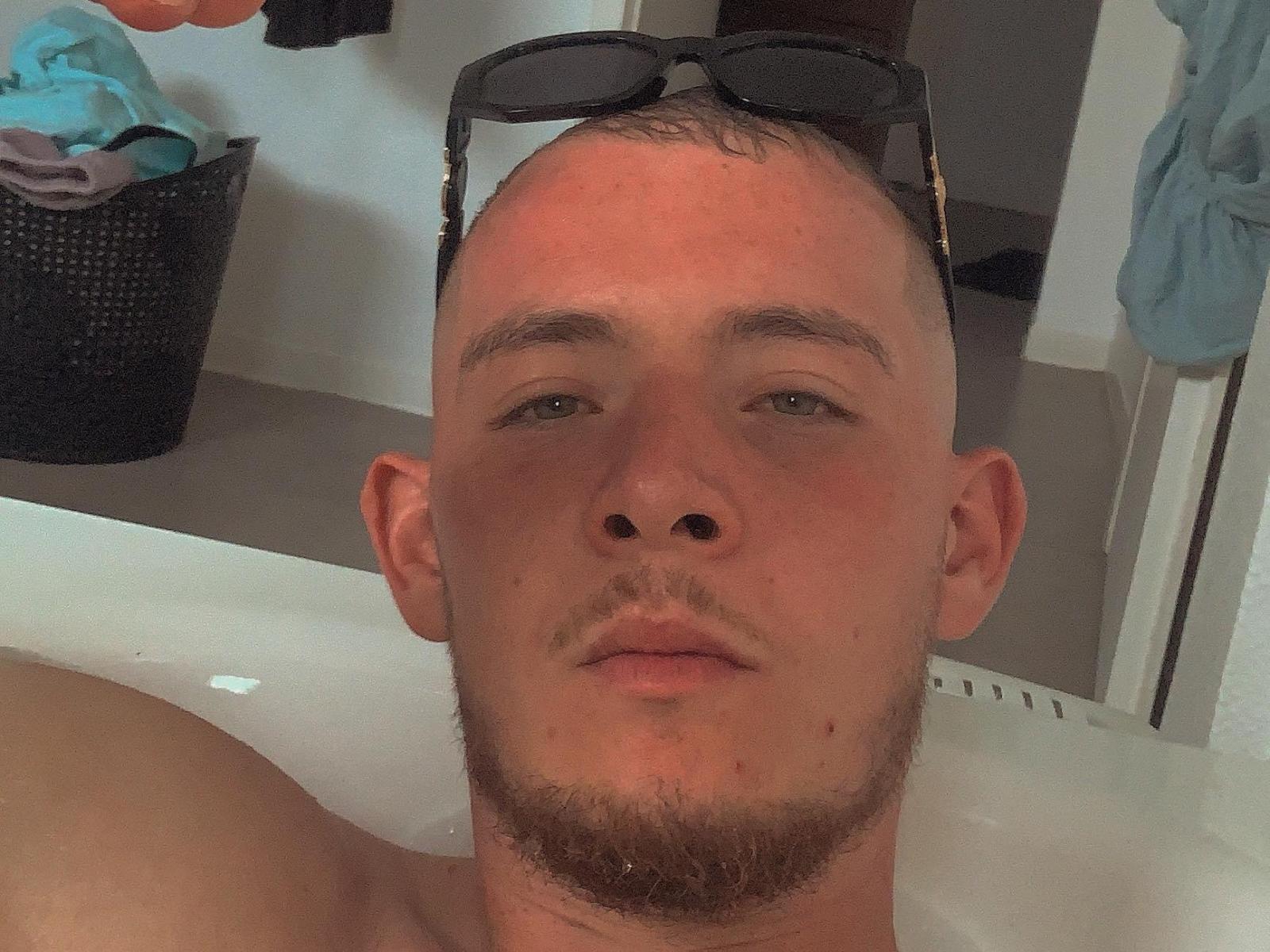 AntoineX has a bald head with sunglasses on top, a beard, and is in a bathtub. His shirtless upper body and pale skin are visible.