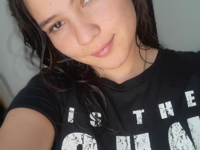 CelesteDash has a cute face with light freckles, brown eyes, and a slight smile. She's wearing a black shirt, and her wet, dark hair is over her shoulder.