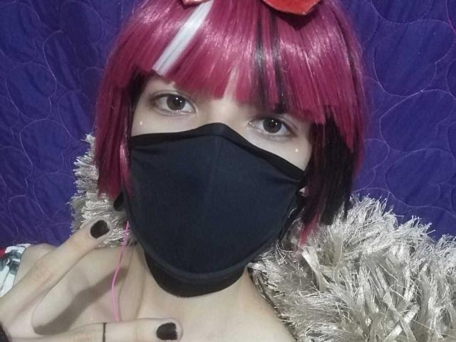 Tulipanti, met roze en witte haren, een zwart masker en zwarte nagels, draagt een zilveren jas met een bontrand en heeft bruine ogen en een rood haaraccessoire..