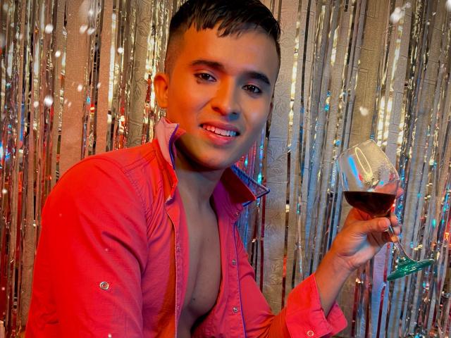 DayanWilly, con cabello negro corto, camisa roja, pecho descubierto, sosteniendo una copa de vino tinto, sonriendo, fondo de cortina plateada, mirando a la cámara, linda, sexy, luz cálida..