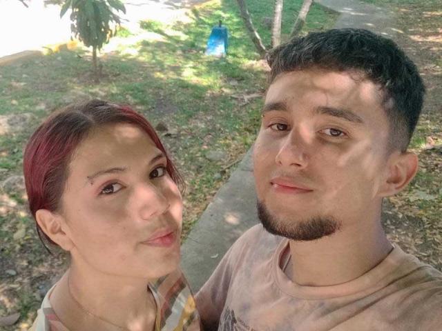 Two SpecialFriendsBenefits with red hair and short dark hair, smiling at the camera. She has small tits, he has a stubby beard and a cute face. They're outdoors.