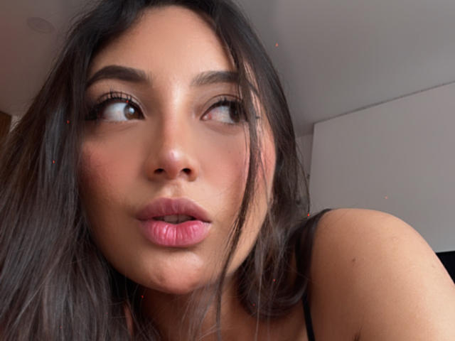 DianaFernandezz ha labbra rosa carnose, occhi marroni che guardano di lato e lunghi capelli scuri, indossa una maglietta nera, con un viso leggermente arrossato e carino..