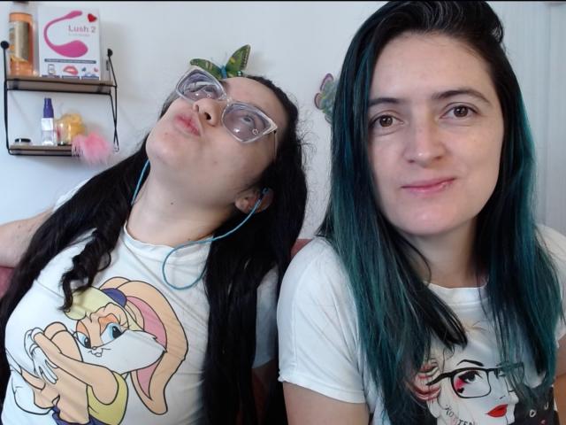 LunaVenus with long black hair, pigtails, and glasses, puckering lips, wearing a Looney Tunes shirt. Another LunaVenus with green-dyed hair, white shirt, and glasses, smiling.