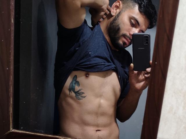 JeffSexy, dark-haired, bearded dude, lifting black shirt, exposing abs, tattoo of fish on left side, holding phone, mirror selfie, muscular, sexy, brown skin, wooden frame.