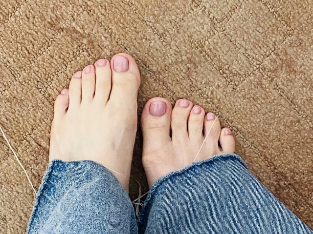 KarKutie's bare feet with pink toenails, slightly dirty blue jeans, and a thin white string between the toes on a textured brown carpet.