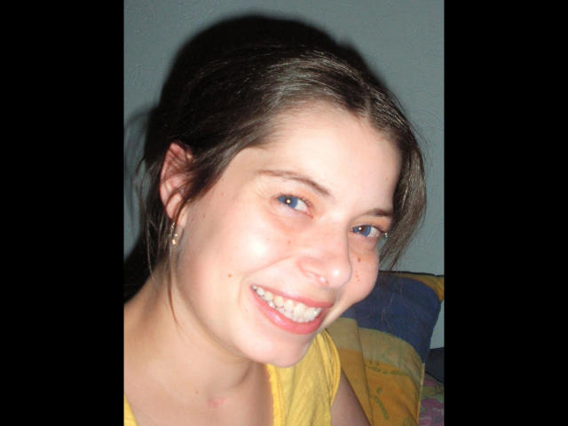 Chiara177-hot has blue eyes, a nose ring, and a smile showing her teeth. She has freckles, brown hair, and wears a yellow shirt with small earrings.