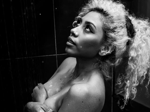 Black-and-white photo of LilithWalker with wet curly blonde hair, crossed arms covering her tits, water droplets on her skin, looking upward with a serious expression.