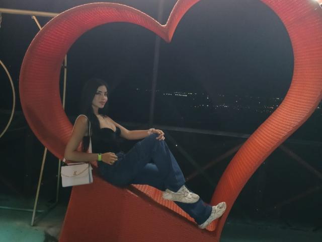 Shantal Turner, con un seno di media grandezza, indossa una maglietta nera, pantaloni blu e scarpe da ginnastica bianche. È seduta all'interno di una struttura metallica a forma di cuore rosso, tiene in mano una borsa bianca. È notte, e sullo sfondo si vedono le luci della città..