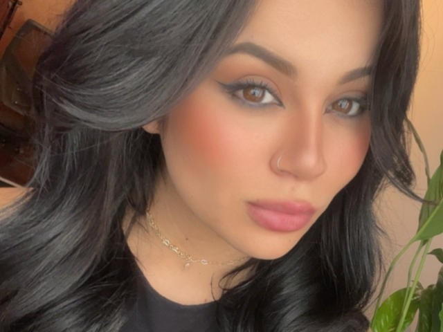 ShantallParis has black wavy hair, brown eyes, thick eyebrows, pink blush, and pink lipstick. She's wearing a nose ring and a gold chain necklace. Her face is centered.