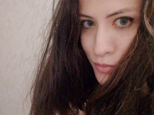 SweetyPrincess69 has long dark brown hair, blue eyes, and a serious expression, with slightly parted pink lips, in a blurry selfie.