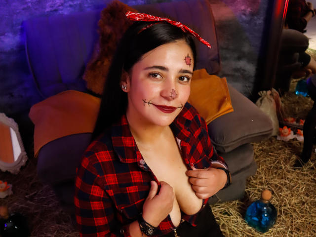 LailaRogerts, a chubby woman with dark hair, red bandana, and black nose ring, has her plaid shirt open, exposing her tits, with fake blood on her face.