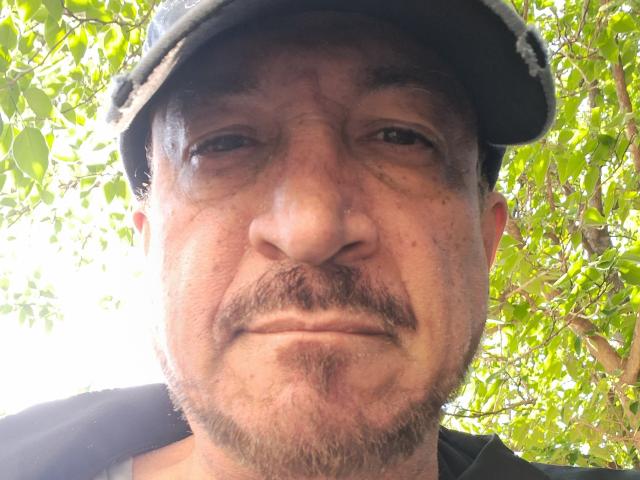 LeonMacK has a dirty, slightly puffy face with a mustache and goatee, wearing a black cap. His skin is tan with visible freckles and he looks tired.