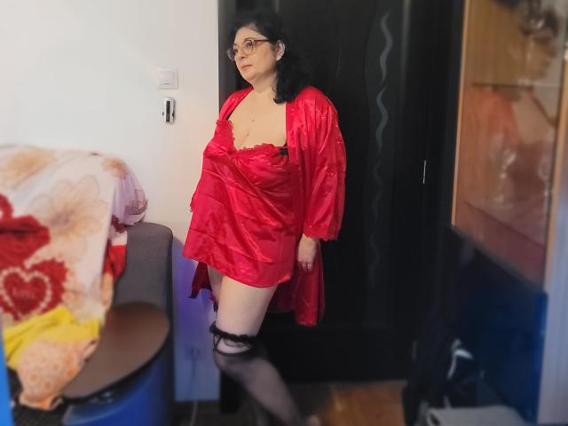 HotAndSexyMature with pale skin, black hair, glasses, wearing red satin robe, black lace top, and thigh stockings, standing in doorway, showing her big ass and small tits.