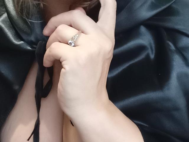 KelliRedhaer's hand with a shiny diamond ring on her finger, gently holding black silk fabric, showcasing her tits and pale skin.