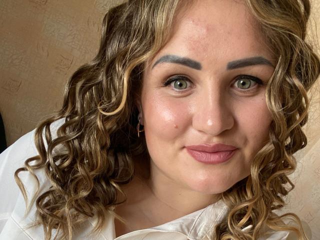 HoneydewWaves heeft krullend bruin haar, groene ogen, dikke wenkbrauwen, roze lippen en een lichte glimlach. Ze draagt een witte blouse met een subtiel patroon. Haar gezicht is licht rood..