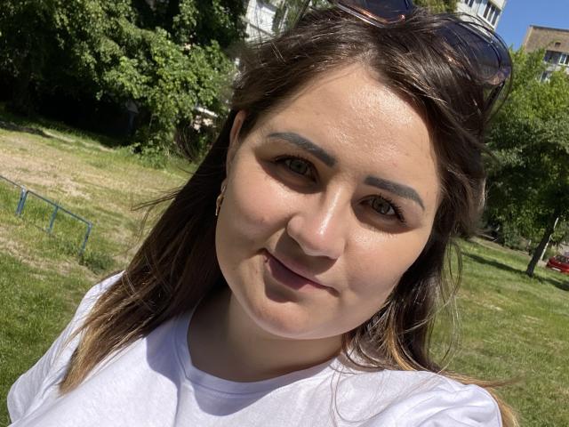 HoneydewWaves tiene una cara redonda con cejas gruesas, ojos verdes y una ligera sonrisa. Lleva una camisa blanca y tiene gafas de sol en la cabeza..