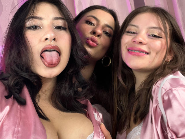 VictoriaAngels with three other women, all sticking out their tongues and wearing pink satin jackets. VictoriaAngels has big tits and a nose ring, the others have pink lipstick.
