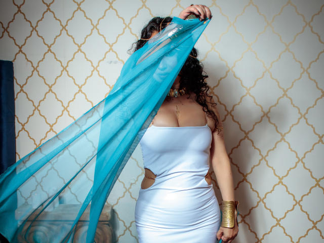 Close-up of a modern art piece with a series of overlapping, abstract, geometric shapes in soft blue, pink, and beige. Shapes have smooth, flat textures with subtle gradients.