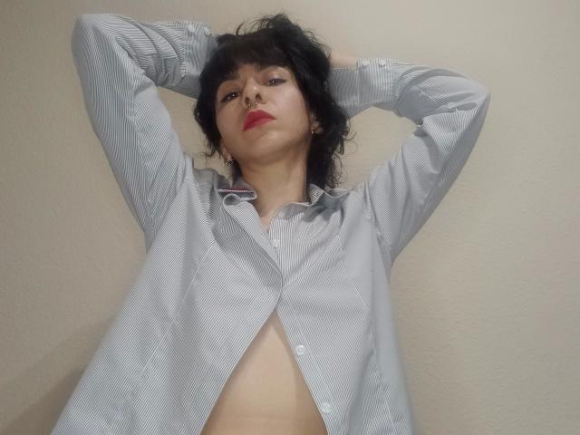 PandoraPurple-hot with short black hair, red lipstick, and a light gray button-up shirt, arms behind head, shirt open, exposing her bare tits and flat stomach.
