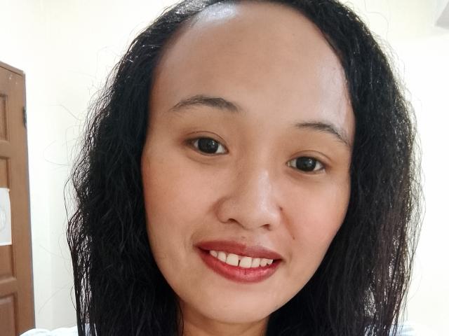 Das Gesicht von Lachey69, mit nassen, schwarzen Haaren, braunen Augen und rotem Lippenstift, zeigt ein leichtes Lächeln. Sie hat eine helle Haut und eine kleine Nase. Ihre Brüste sind nicht sichtbar..