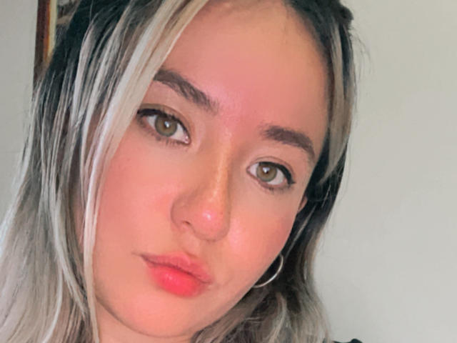 NickySexFire has blonde and black hair, green eyes, and pink lips, with a slight pout. She's wearing a hoop earring and has a light pinkish-red skin tone.