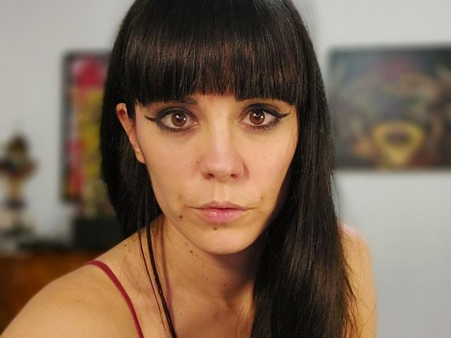 OrianaLaFrancaise has dark brown eyes with thick black eyeliner, straight black bangs, and a serious expression. She's wearing a red spaghetti strap top.