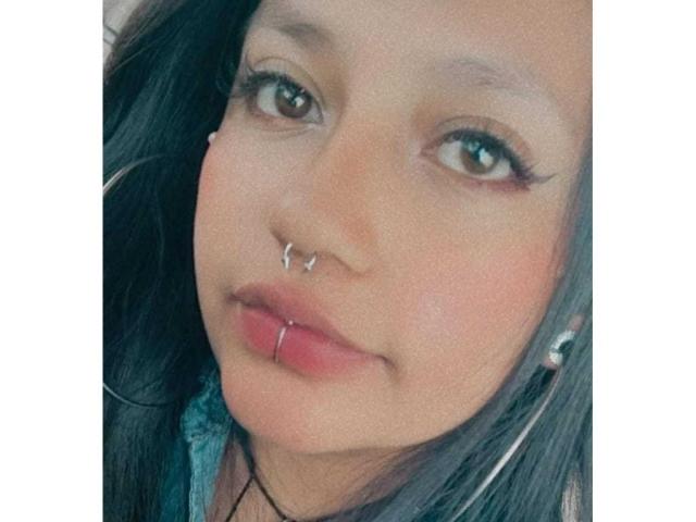 LilithAbrahel69 has a cute face with green eyes, a silver nose ring, a septum ring, a lip ring, and long dark hair, wearing a green shirt.