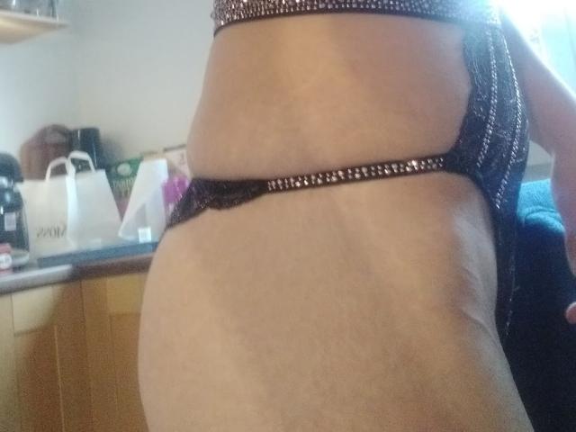 Side view of HotSexyLady69's belly and black lace panties with sparkling trim, showing her soft, slightly saggy belly and light brown skin. Her ass is partially visible.