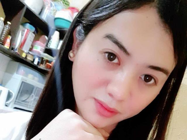 YourSophie has pale skin, brown eyes, and long black hair. She's resting her chin on her hand with a slight smile, showing pink lips and small earrings.