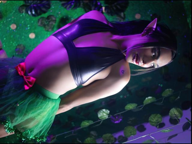 KittyQueeny with elf ears, purple glow, wearing a black leather top and green tulle skirt with a red bow, exposing her small tits and tattoo on her right shoulder.