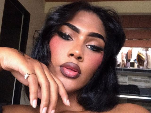 CristinaMontiel has dark, wavy hair, bold eyebrows, pink blush, and glossy pink lips. She's sticking out her tongue, showing a ring on her finger.