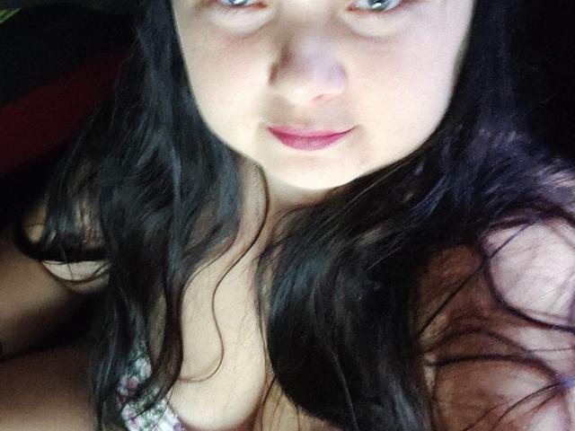 DorothySummer has pale skin, long black hair, blue eyes, and is looking up with a slight smile, showing her small tits and pink lips. She's wearing a floral top.