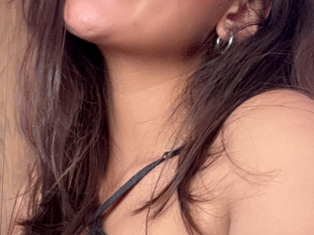 DianaFernandezz's face is partially visible, showing her pouty lips and long brown hair. She's wearing a black strap and silver hoop earrings, with a tan neck.