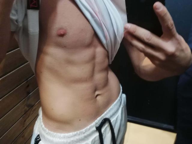 DragMan69's toned abs, a small, pink nipple, and a flat stomach, wearing white, loose shorts, with a hand pulling up a shirt, exposing the side.