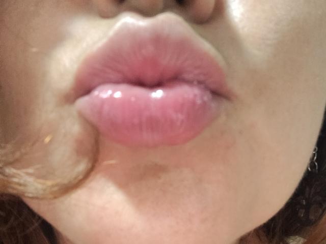 Le labbra rosa e gonfie di SakotoDika sono al centro dell'immagine, leggermente aperte, con un accenno del suo labbro superiore e del mento visibili. La sua pelle è chiara..
