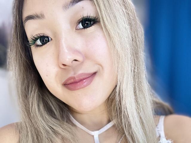 RenyLime a les cheveux blond clair, des yeux verts avec de longues cils noirs, des lèvres roses et brillantes, et un joli sourire. Elle porte un haut blanc avec un col en V..