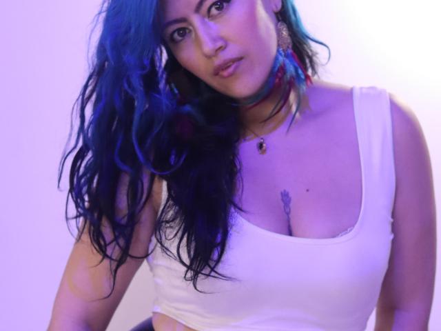 Ailich with blue-tinted wavy hair, white tank top, showing her tits, wearing a red choker and earrings, looking down, light purple glow.