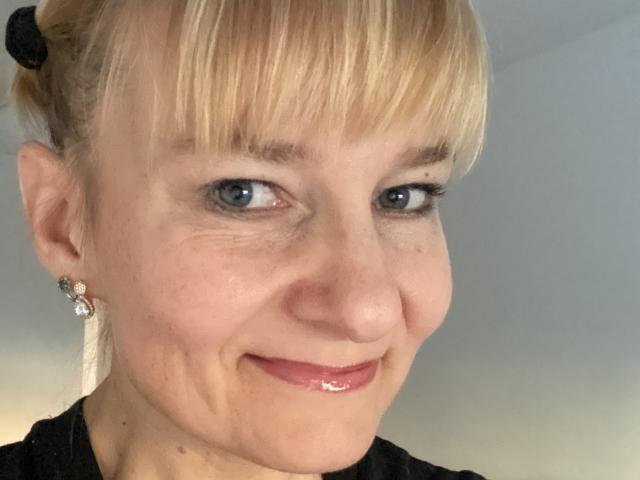 Digital illustration of a flat, stylized coat of arms with a central red emblem and a smaller black emblem in the bottom right. Clean, minimalist design with bold colors.