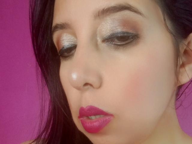 SublimeMature hat schimmernden silbernen Lidschatten, dunklen Eyeliner und pinken Lippenstift. Ihr violett-schwarzes Haar ist teilweise sichtbar. Sie hat einen hellen Hautton und ein leicht gerötetes Gesicht..